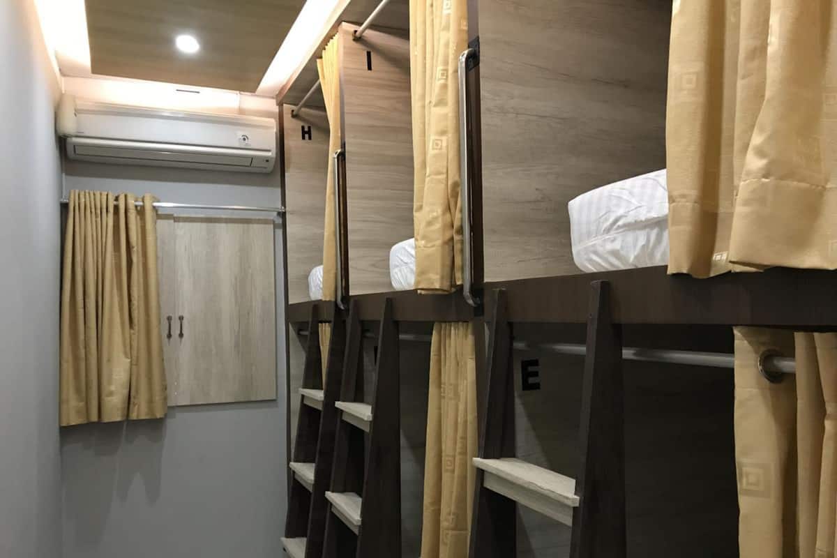 A compact hotel room with bunk beds, a wardrobe, and a curtain.