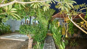 A garden pathway leading to a house with a tiled roof, surrounded by lush greenery and trees. - Kawans Inn Lembongan (Lembongan Island)