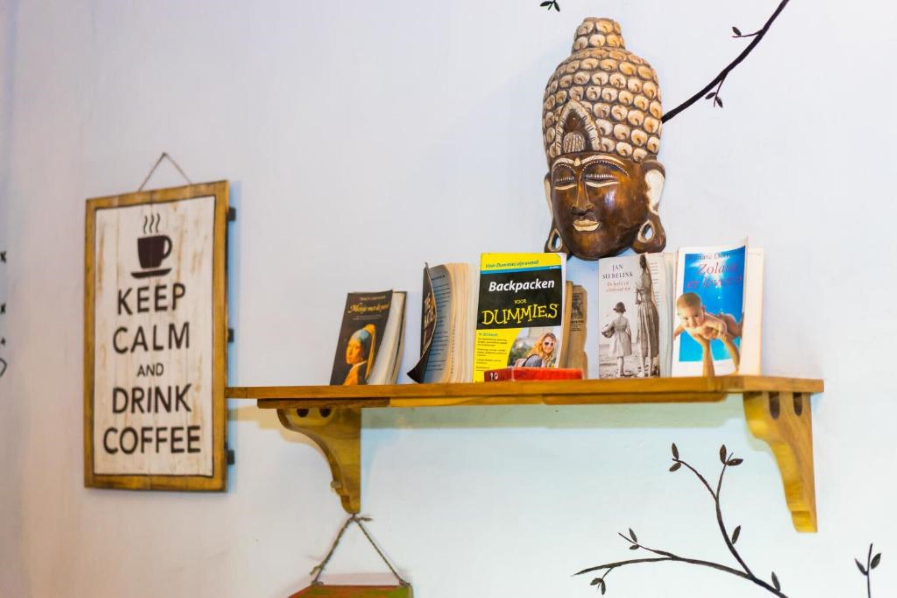 A shelf with books and a Buddha head sculpture.