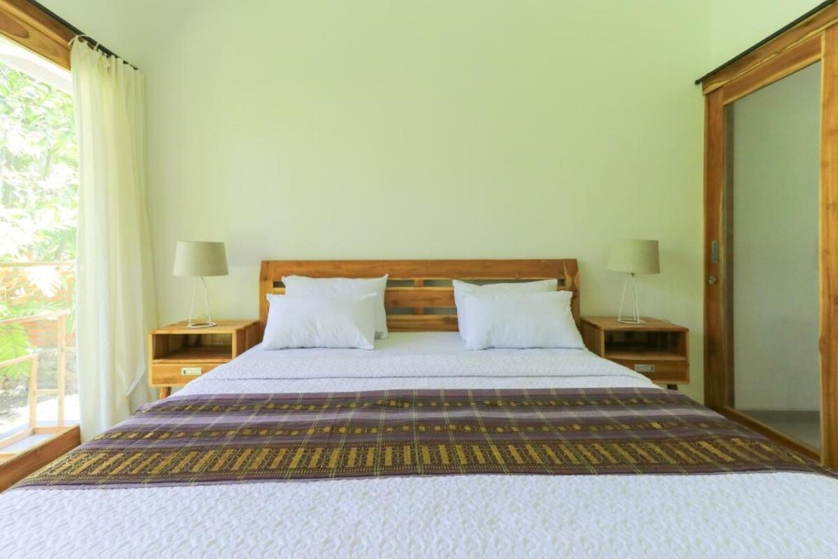 A bedroom with a bed, two nightstands, and a wooden wardrobe.