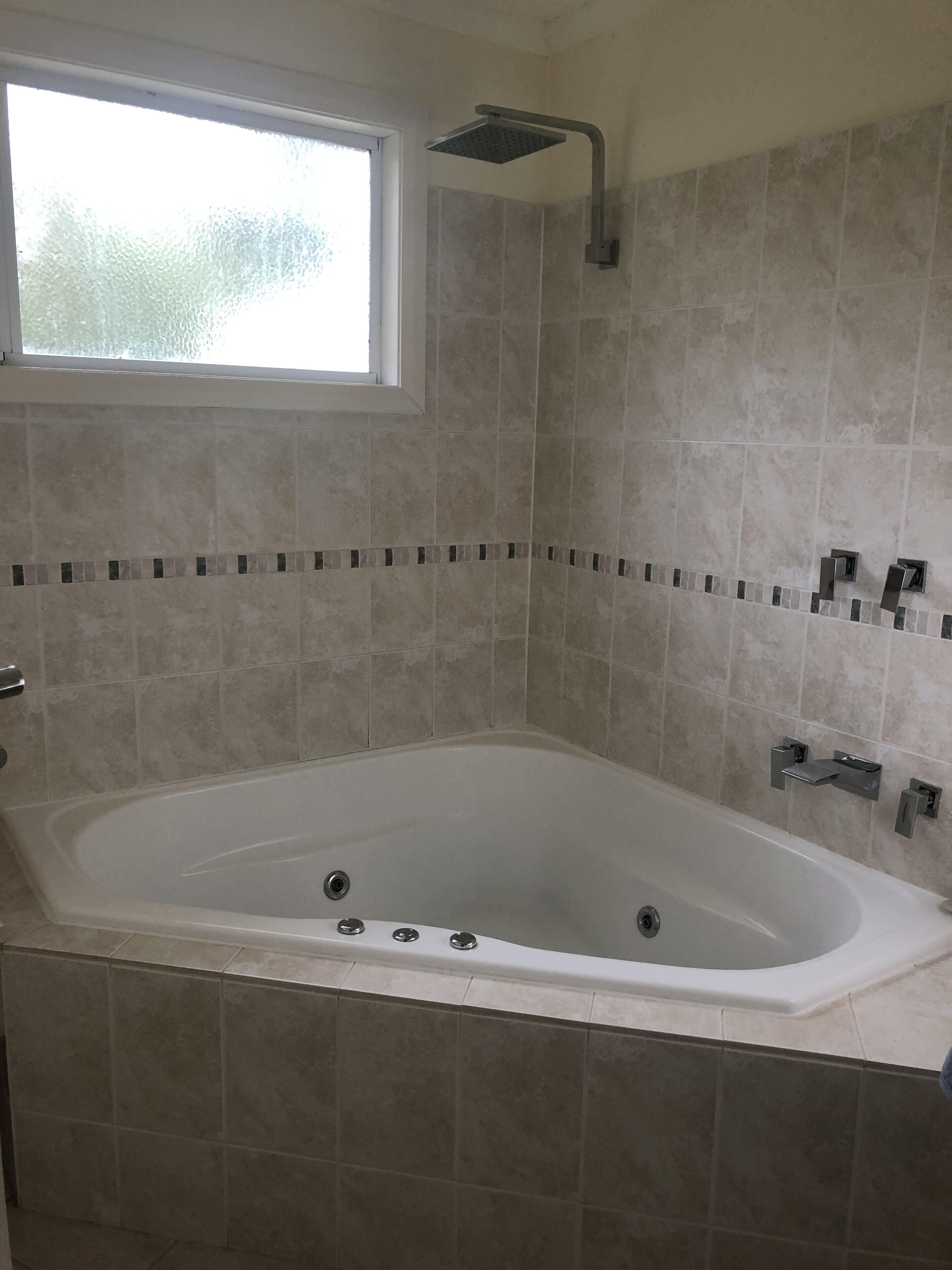 A modern bathroom with a freestanding bathtub, a showerhead, and a window providing natural light.