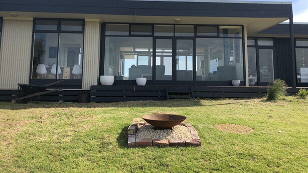 Una casa moderna con ampie finestre, un braciere e un piccolo giardino.