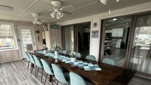 Ein geräumiger Essbereich mit einem langen Holztisch, türkisfarbenen Stühlen und Deckenventilatoren.