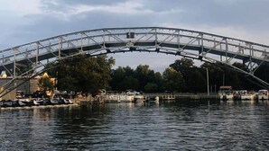 Eine große, bogenförmige Brücke über dem Wasser, darunter Schiffe im Hafen.