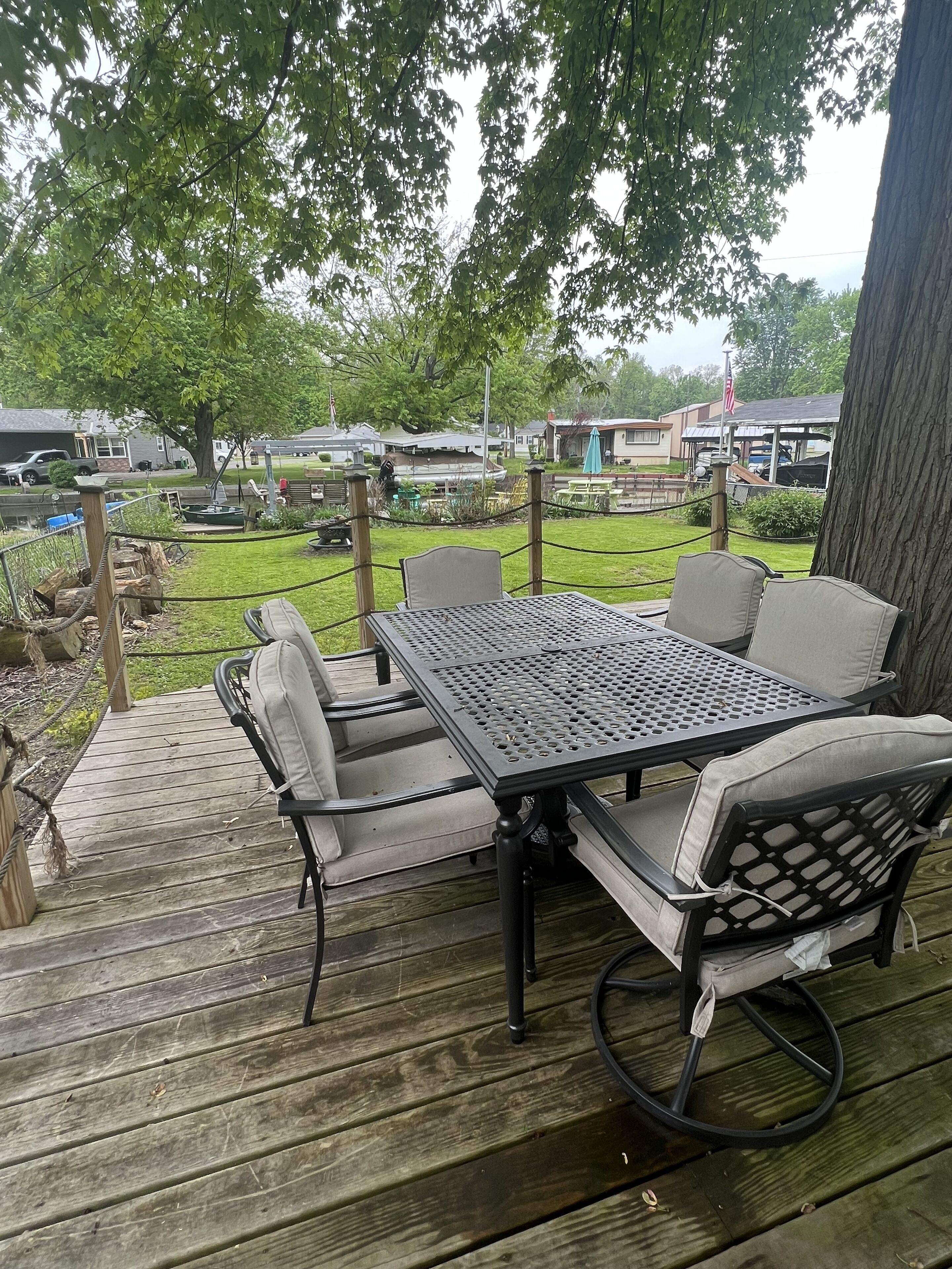 Une terrasse extérieure avec une table et des chaises en métal, entourée d’une plateforme en bois et d’une clôture en corde.