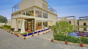 A modern hotel with a two-story structure, large windows, and a swimming pool area. - The Kumbha Residency-Luxury Resort and Spa (Kumbhalgarh)
