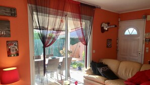 Ein Wohnzimmer mit einem Glastisch, einem beigefarbenen Sofa und einer roten Lampe.