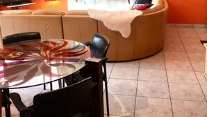 Ein Wohnzimmer mit Glastisch, Ledersofa und Fernseher.