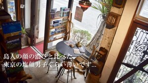 A cozy room with a wooden table, a hanging lamp, and a view of the street outside. - GOLDEN MILE Hostel (Amami)