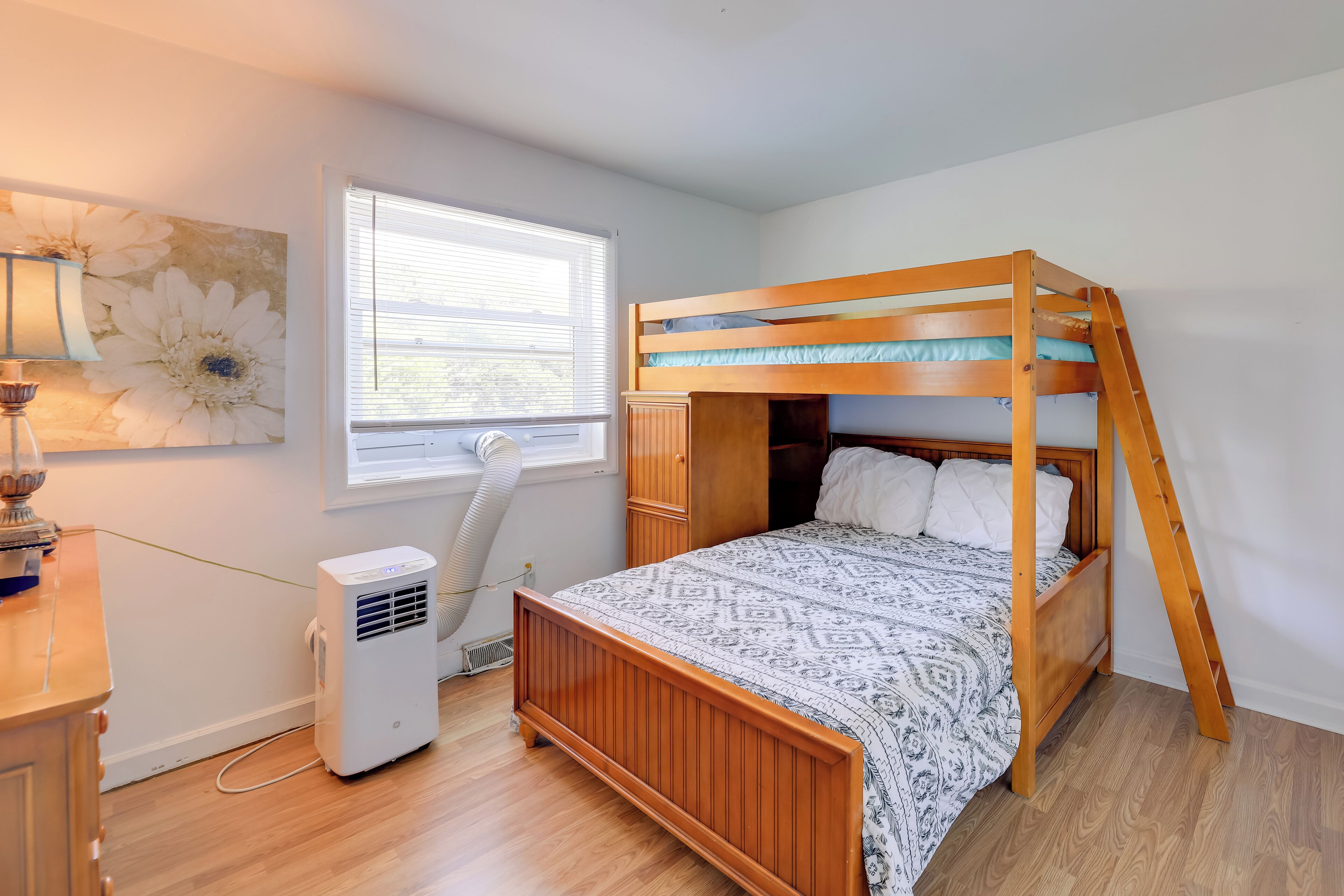 A bedroom with a bunk bed, a window with blinds, a radiator, and a wall-mounted lamp.