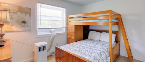 Une chambre avec un lit superposé, une fenêtre avec des stores, un radiateur et une lampe fixée au mur.