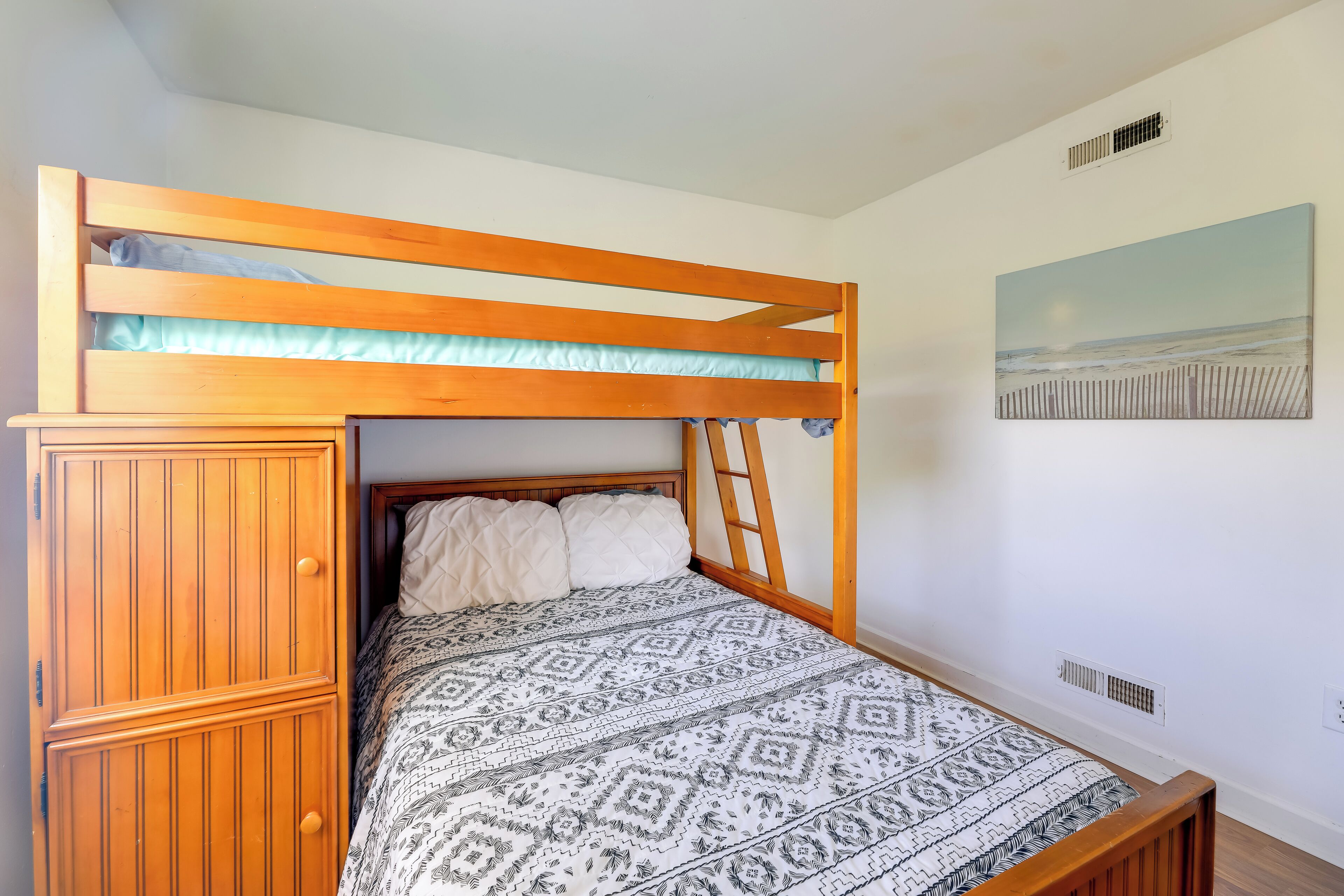 A bunk bed with a wooden headboard, a patterned bedspread, and a wardrobe with vertical slats.