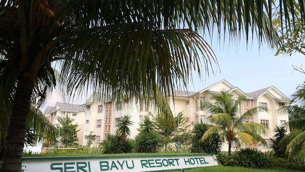 A sign for the Seri Bayu Resort Hotel surrounded by lush greenery and palm trees. - Seri Bayu Resort (Sungai Pelek)