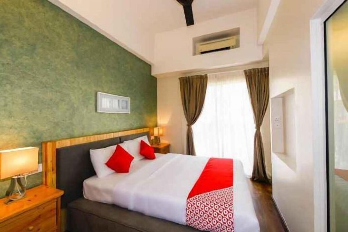Una habitación de hotel con cama, mesita de noche, lámpara y cortinas.