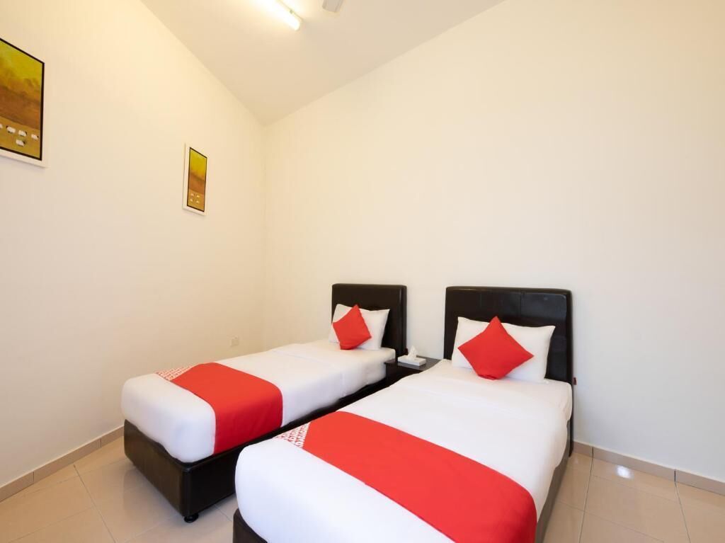 A hotel room with two single beds, each with a red and white bedspread and matching pillows.