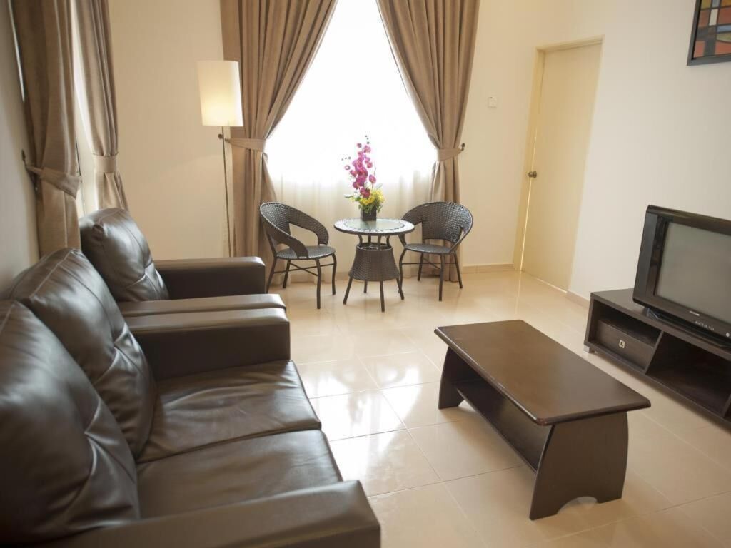 A living room with a sofa, a coffee table, a TV, and a small table with chairs.