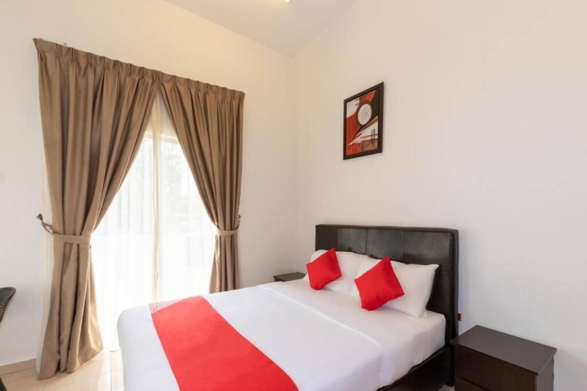 Une chambre d’hôtel avec un lit, une table de chevet, une commode et une fenêtre avec des rideaux.