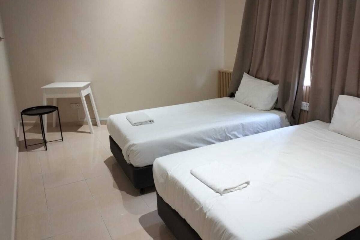 Une chambre d’hôtel avec deux lits simples, une petite table et une chaise.