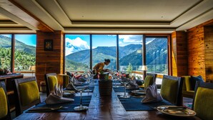 A dining area with a mountain view, wooden walls, and a table set for a meal. - The Postcard Dewa Thimphu (Thimphu)