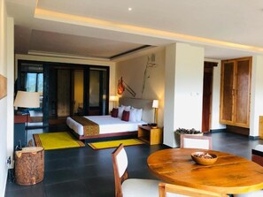 A modern hotel room with a large bed, a round dining table, and a view of the city. - The Postcard Dewa  Thimphu (Thimphu)