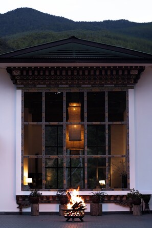 A building with large windows, a fireplace, and potted plants. - The Postcard Dewa  Thimphu (Thimphu)