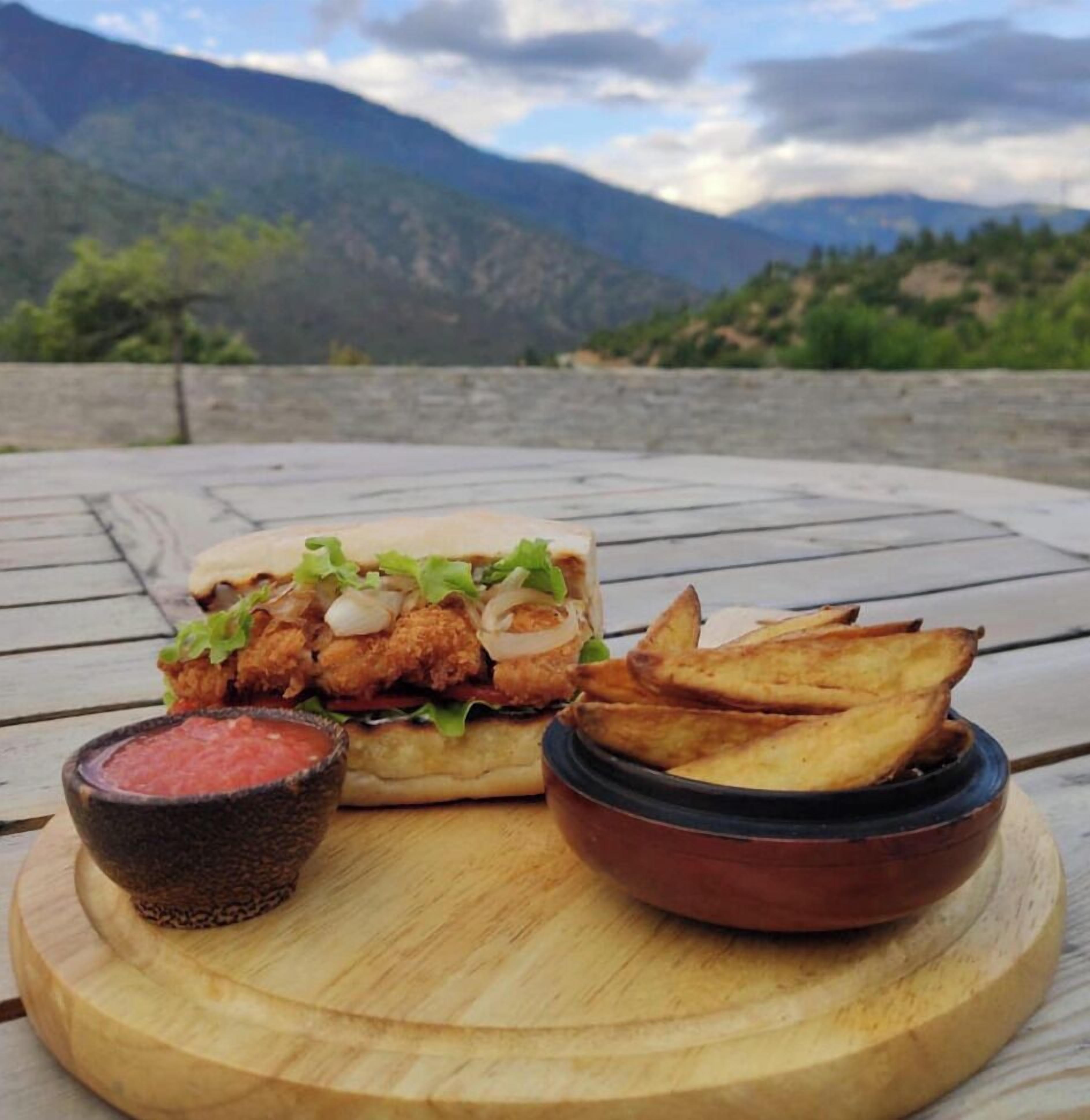 A meal on a wooden table with mountains in the background.