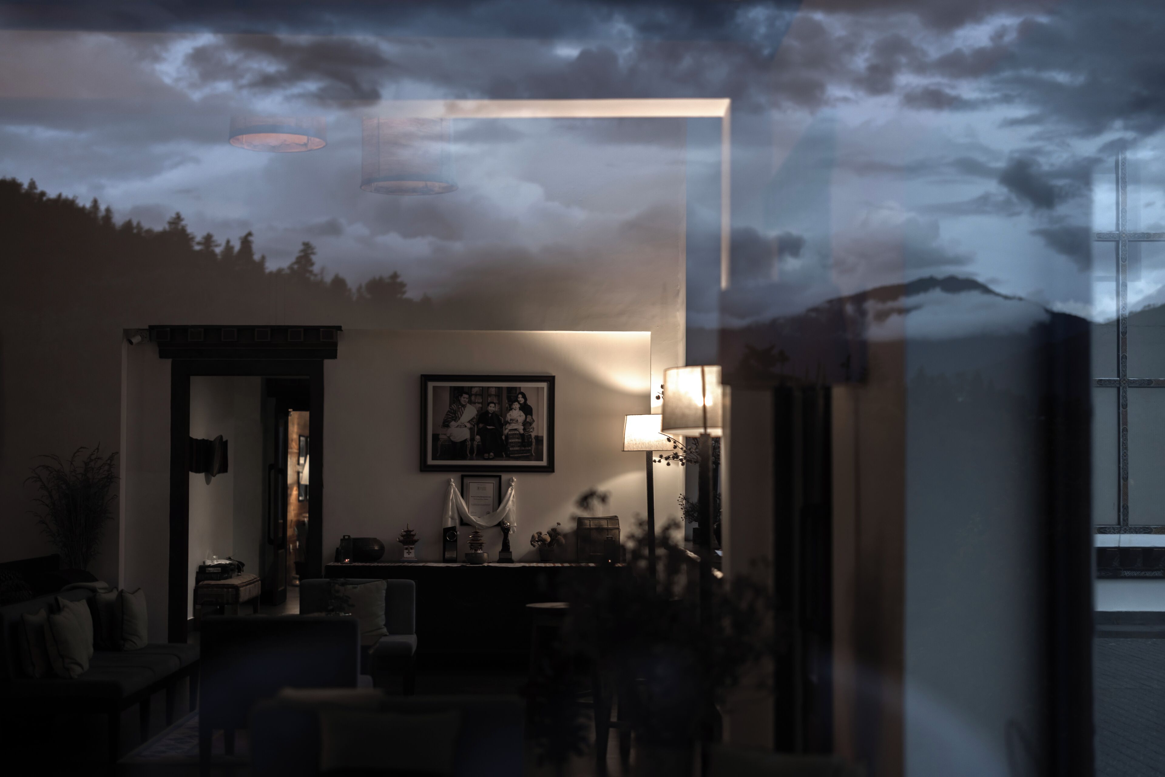 A dimly lit room with a framed picture on the wall, a lamp, and a window.