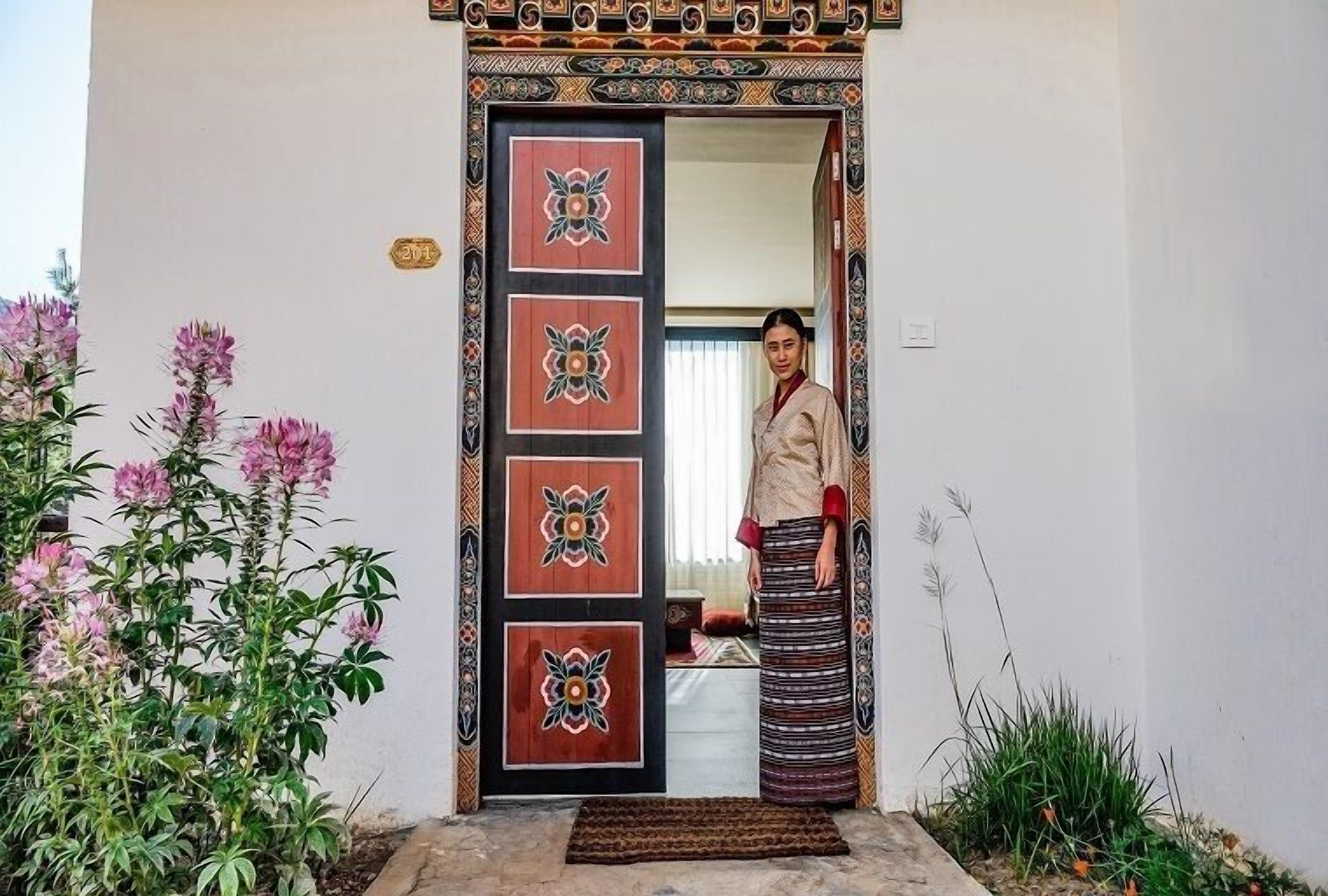 Una puerta tradicional con motivos florales y una placa de número, que da acceso a un espacio interior.