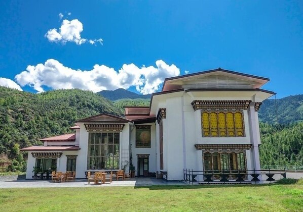 A two-story building with a traditional architectural style, featuring large windows and a balcony. - The Postcard Dewa  Thimphu (Thimphu)
