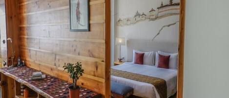 A wooden room with a bed, a desk, and a wall-mounted picture.