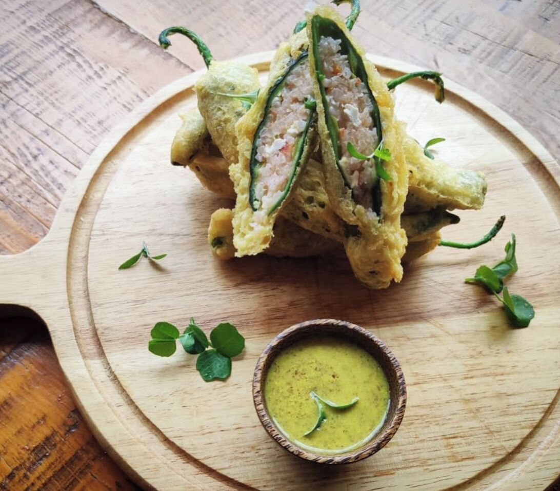 Un plato con salsa verde y un pequeño recipiente con salsa sobre una tabla de madera.