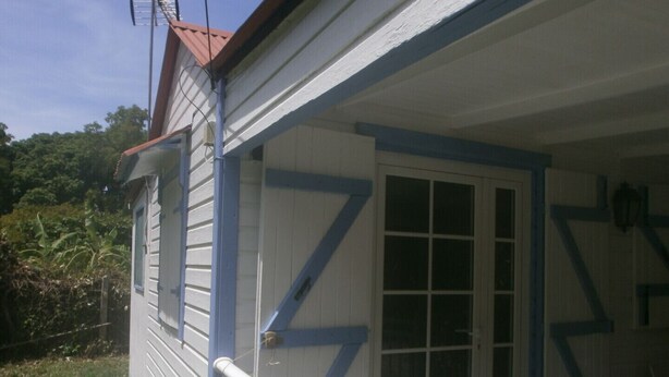 Een huis met een witte gevel, blauwe details en een rood dak.