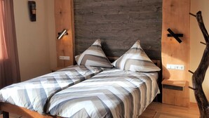 Una cama doble con ropa de cama a rayas, un cabecero de madera y una mesita de noche con una lámpara.