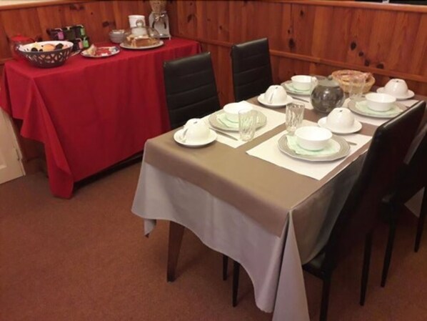 Un comedor con una mesa dispuesta para cuatro, incluyendo platos, vasos y un frutero.