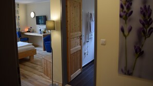 Une pièce comprenant un lit, un bureau, une chaise, un téléviseur et une porte.