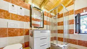 A bathroom with a toilet, a sink with a mirror, and a shower enclosure.