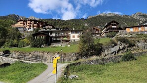 A mountain resort with multiple chalet-style buildings, a stone bridge, and a clear sky.