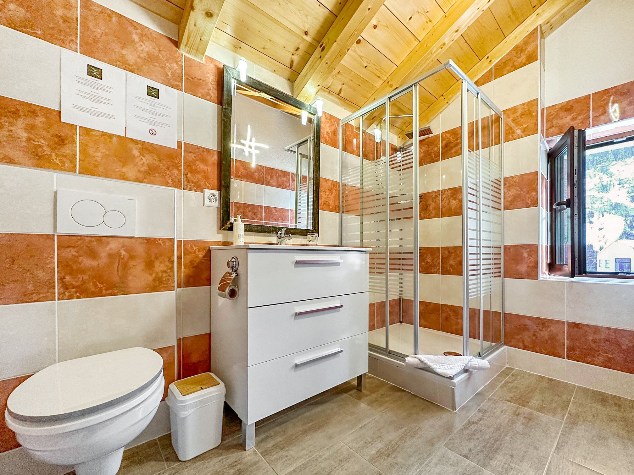Een badkamer met toilet, wastafel met spiegel en douchecabine.