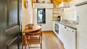 A kitchen with wooden beams, a dining table with chairs, a refrigerator, and a window with a view.