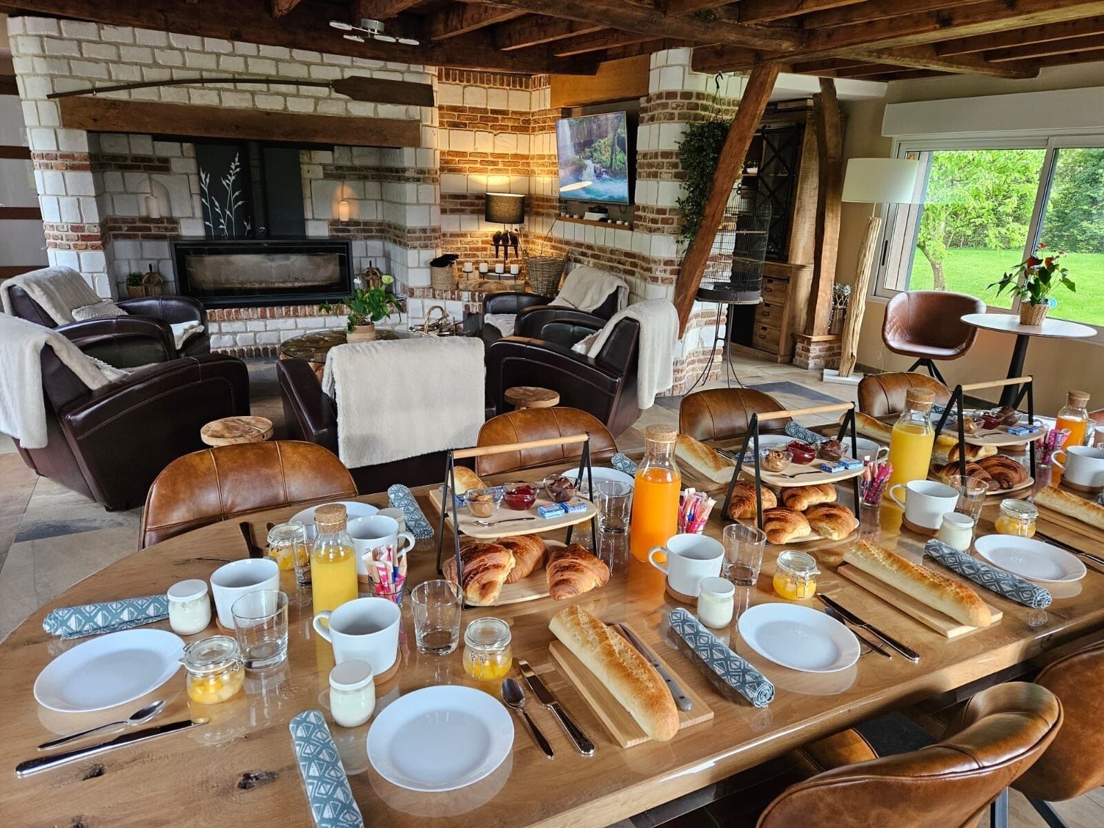 A cozy outdoor dining area with a brick fireplace, leather seating, and a breakfast spread.