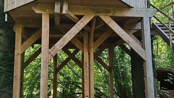 A wooden structure with a platform and stairs, surrounded by trees.