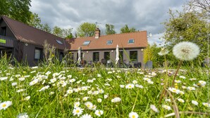 A house with a red roof, multiple windows, and a garden with white flowers. - Le Domaine de Wail Legends Resort (Wail)