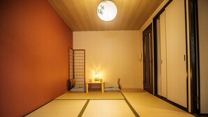 A traditional Japanese room with tatami flooring, a shoji screen, a small table with a candle, and sliding doors.