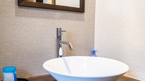 A bathroom with a white sink, a chrome faucet, and a blue soap dispenser.