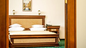 Ein hölzernes Bett mit einem gewobenen Kopfteil, zwei Nachttischlampen und ein Gemälde einer Brücke an der Wand.