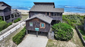 A coastal house with a wooden exterior, a deck, and a view of the ocean. - OCEANFRONT, Ocean views, screened porch, NP15-1, Pelican Dunes (Duck)