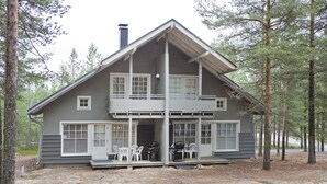 Une cabane à deux étages avec un balcon, entourée d’arbres.