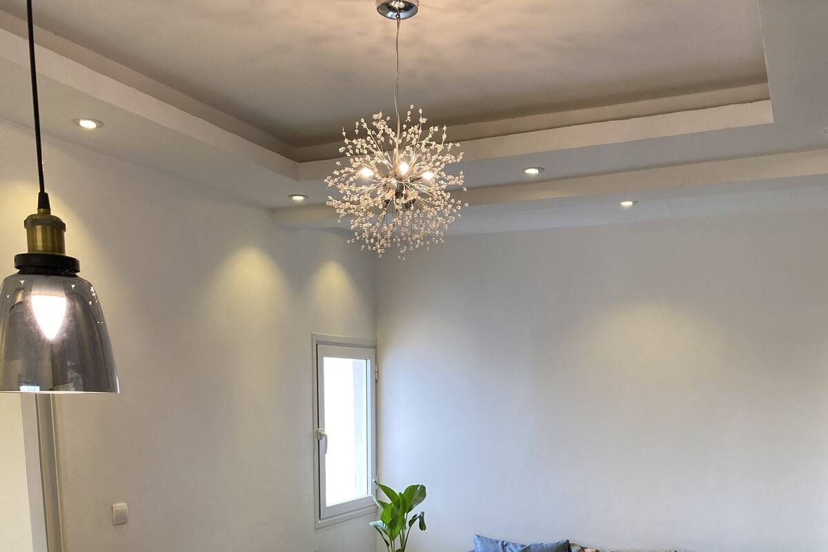 A modern living room with a sectional sofa, a dining table, and a chandelier.