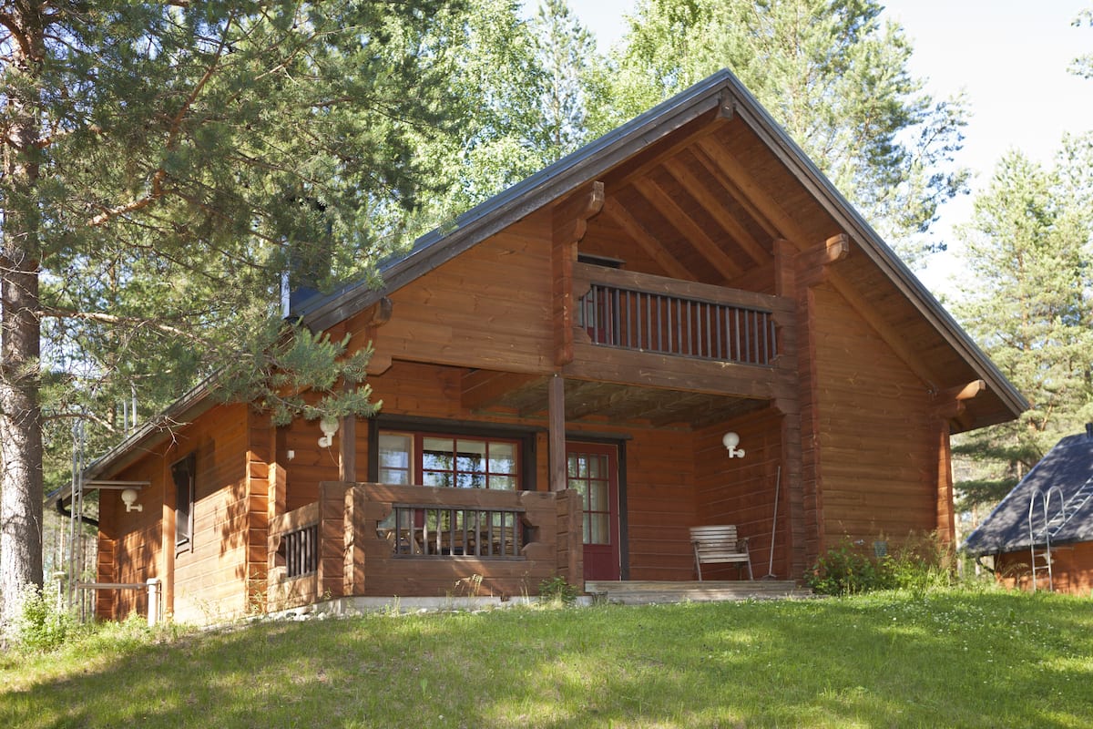 Eine rustikale Holzhütte mit Balkon, großen Fenstern und einer Veranda.