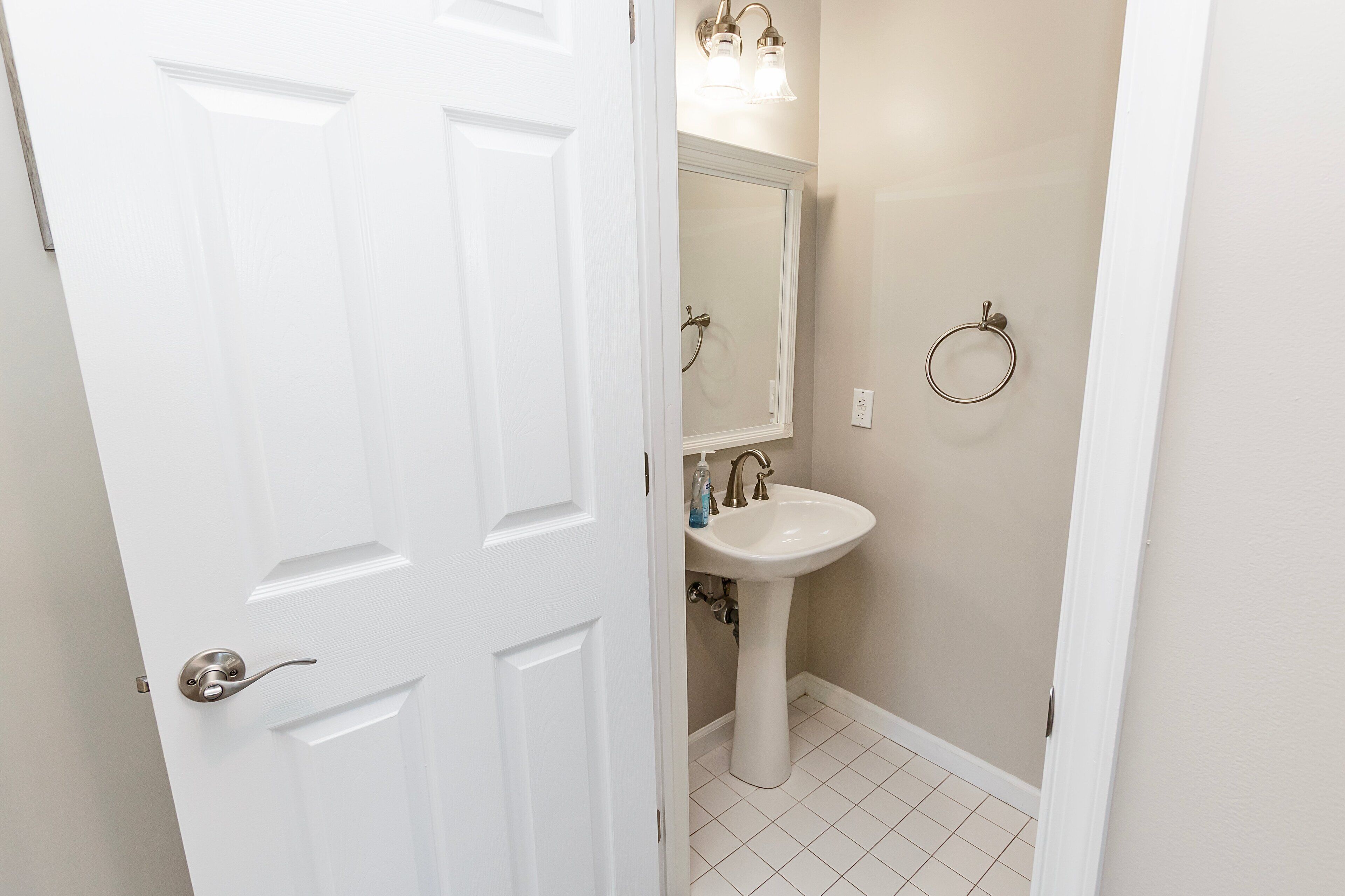 Une salle de bain avec une porte blanche, un lavabo, un miroir et un porte-serviette.